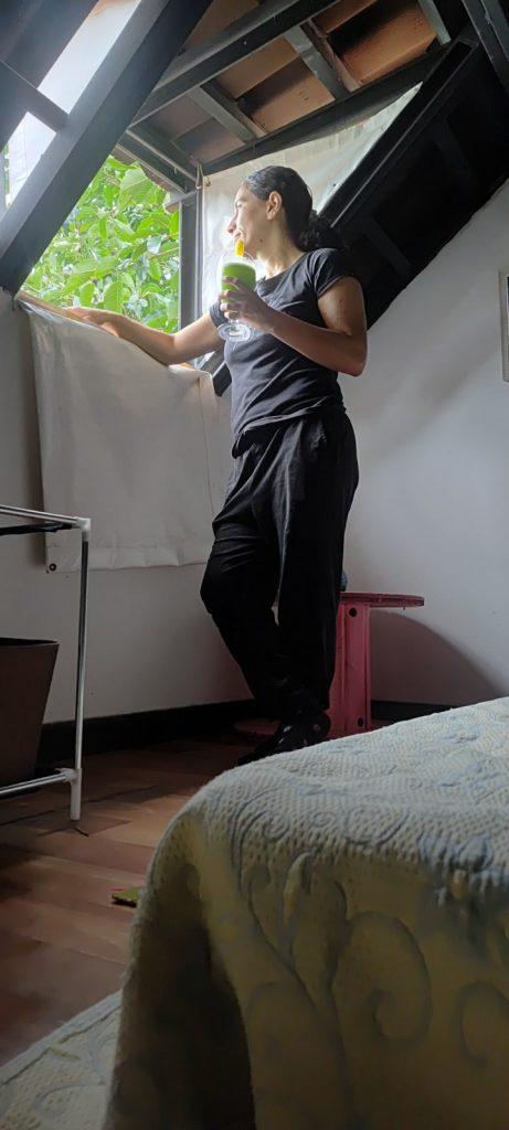 mujer observando paisaje por la ventana del chalet disfrutando una bebida